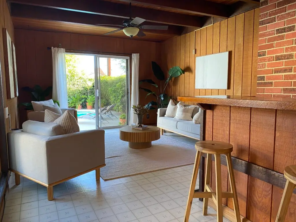 Warm wood-paneled lounge room at 736 Irving Drive Burbank with sliding doors opening to the pool, built-in bar, and mid-century seating.